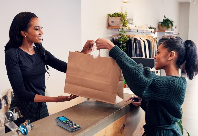 woman accepting shopping bag from shop assistant